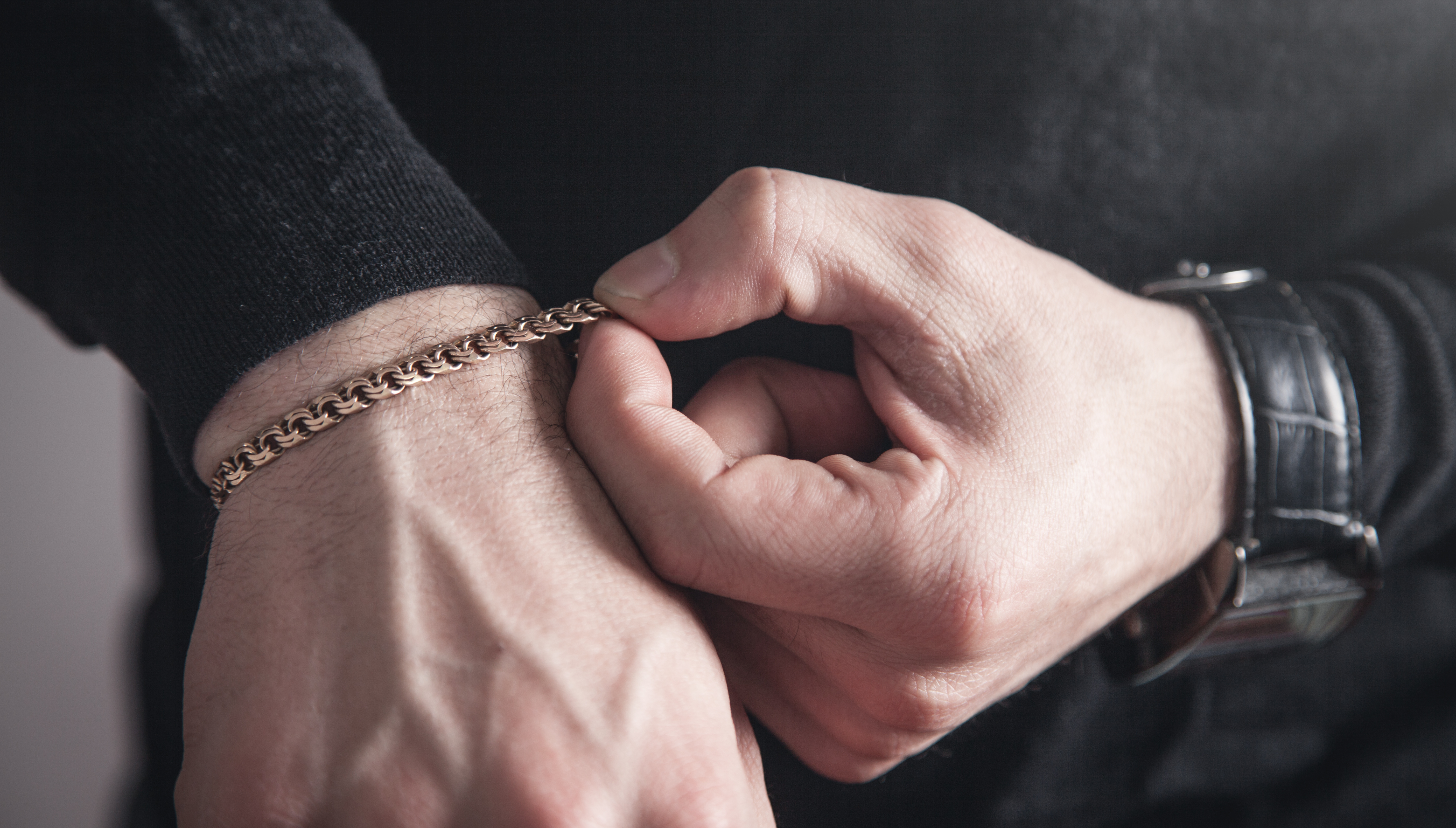 A man putting on a chain bracelet