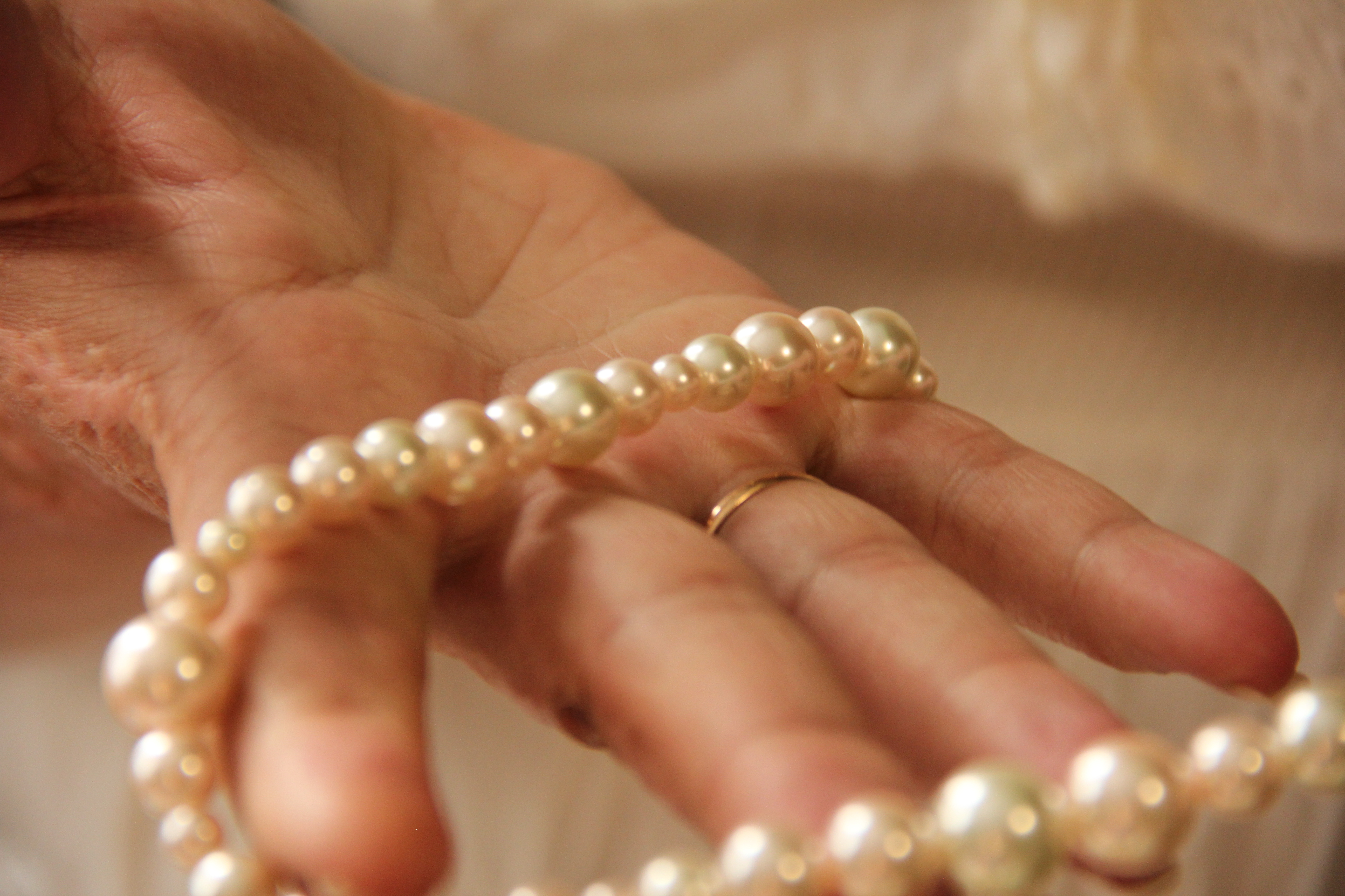 A closeup of a man's hand holding a strand of pearls